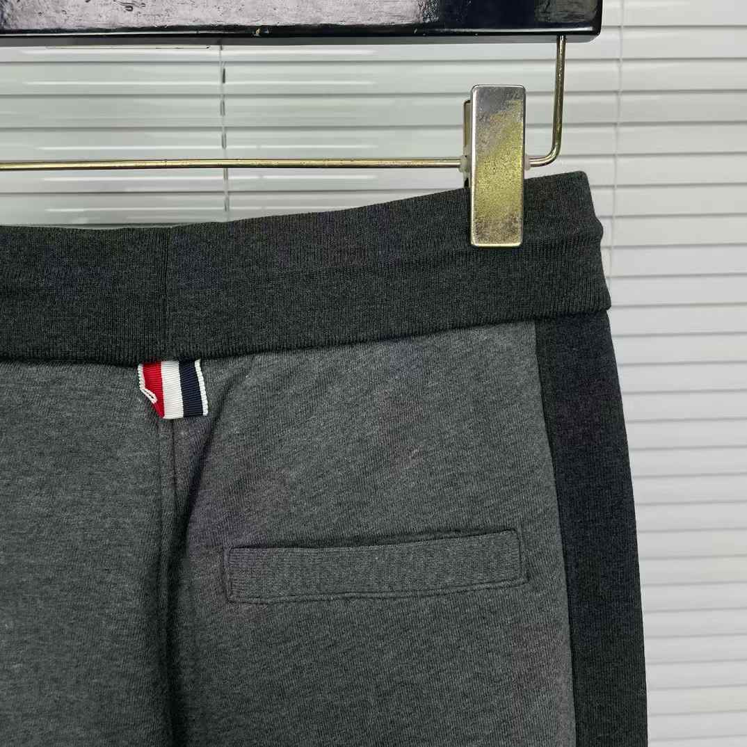 Thom Browne men's gray cotton jersey sweatpants featuring a color-block design and the signature 4-bar stripe detail on the side