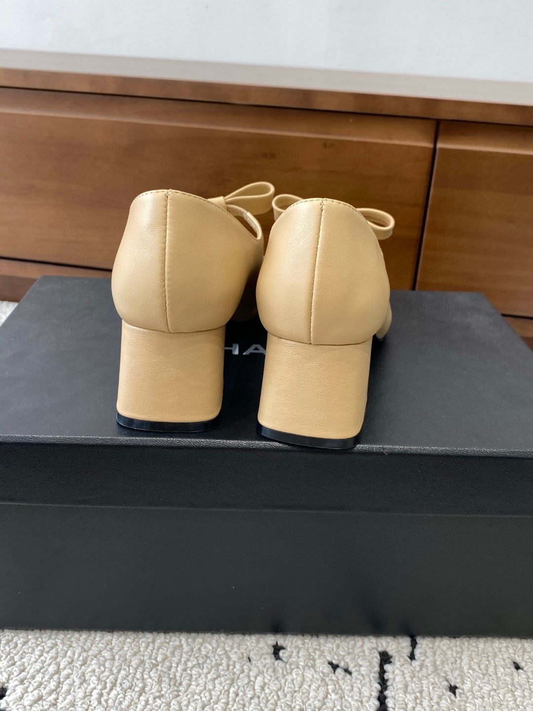 Chanel Mary Jane heels are designed in a classic two-tone beige and black leather style with a sturdy block heel and a ribbon strap detail.