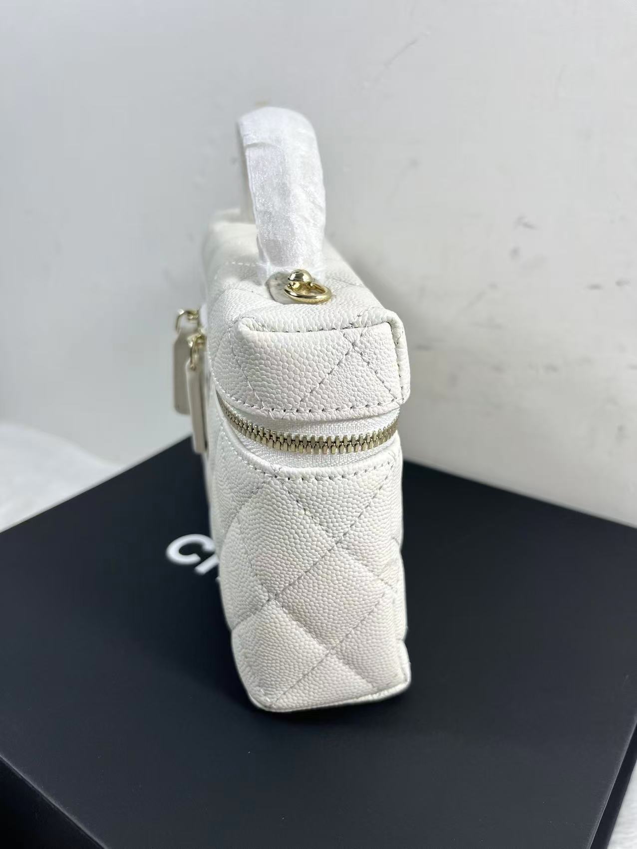 Chanel vanity case likely crafted from white quilted caviar leather featuring gold-tone hardware