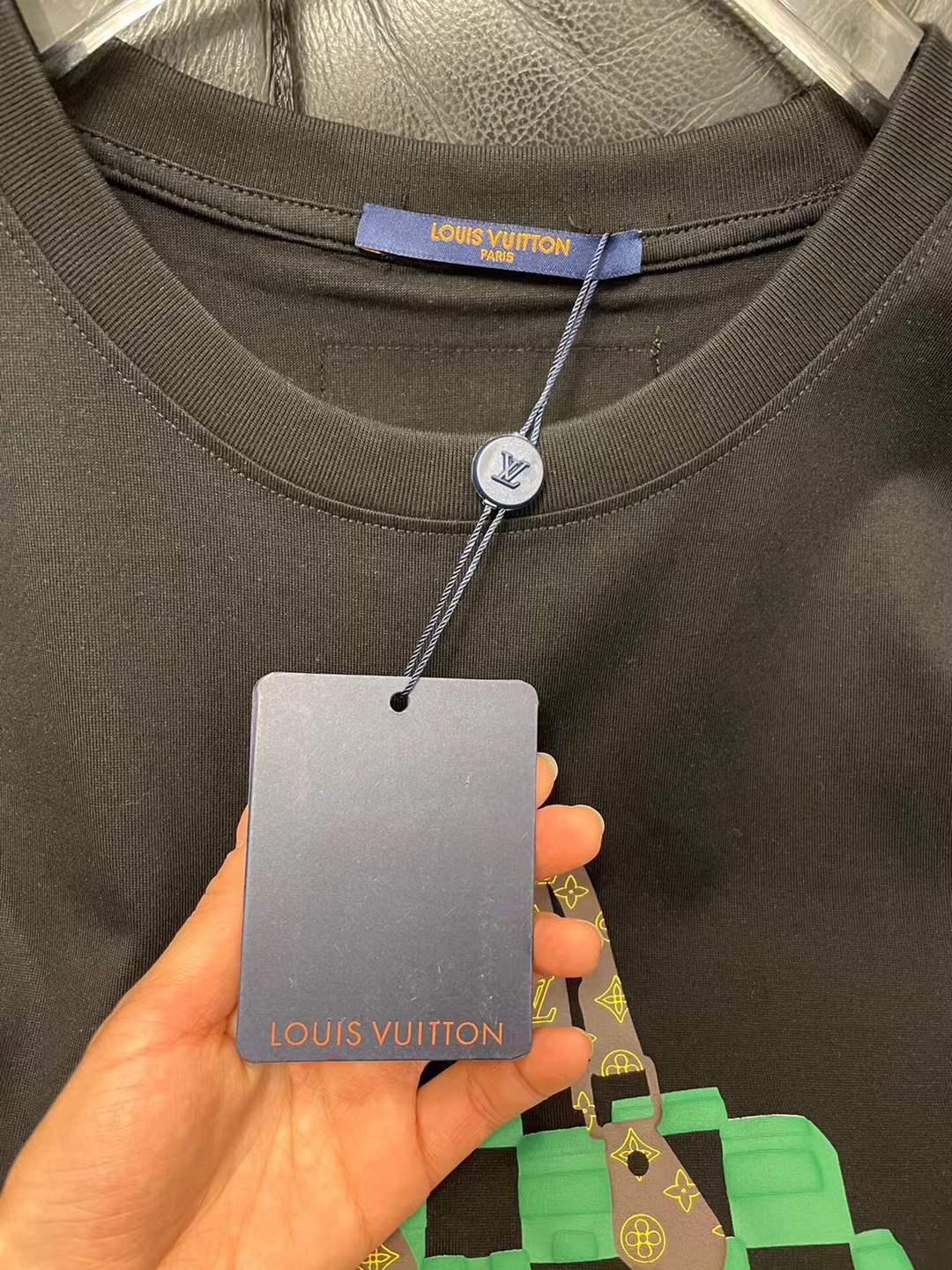 LV t-shirt features a distinctive green and black checkered graphic print resembling one of the brand's iconic handbags