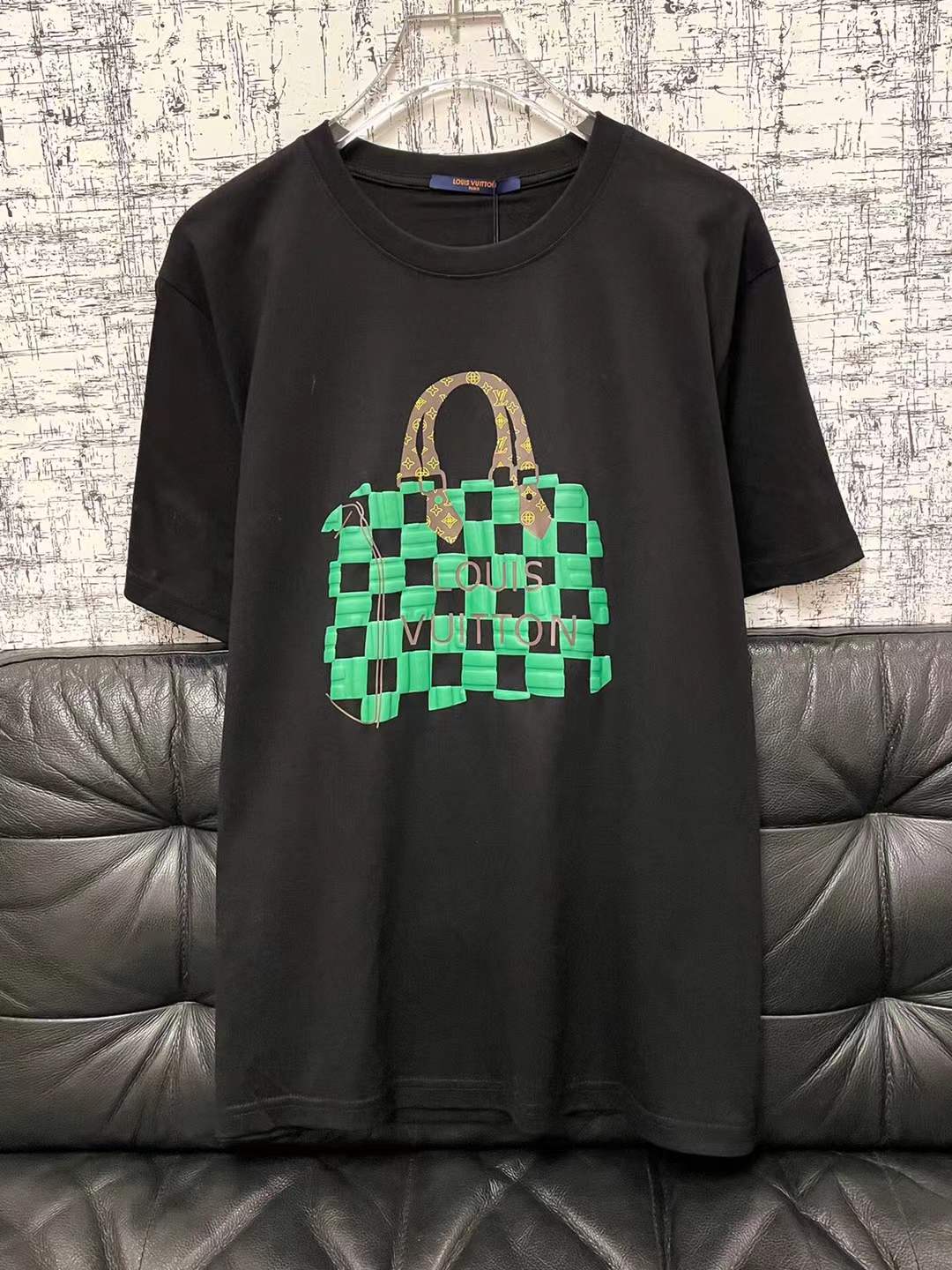 LV t-shirt features a distinctive green and black checkered graphic print resembling one of the brand's iconic handbags