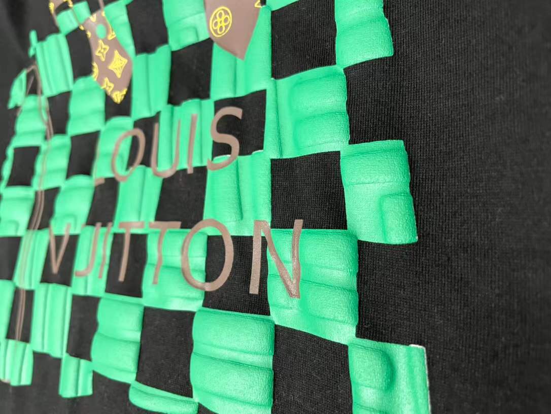 LV t-shirt features a distinctive green and black checkered graphic print resembling one of the brand's iconic handbags
