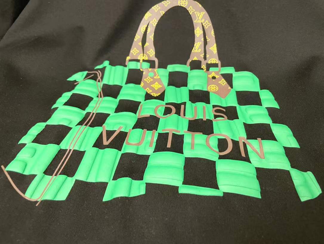 LV t-shirt features a distinctive green and black checkered graphic print resembling one of the brand's iconic handbags