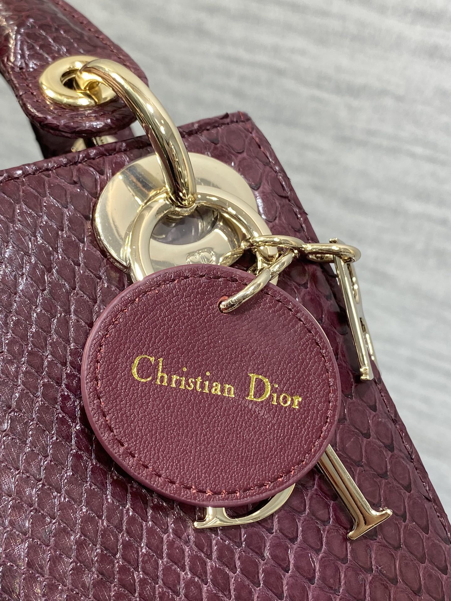 Christian Dior burgundy python leather Mini Lady Dior bag featuring gold-tone hardware and signature charms