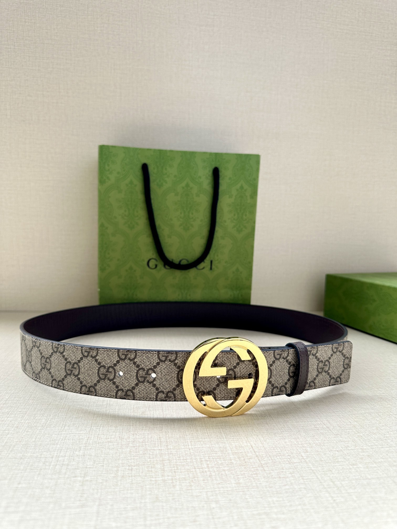 Gucci GG Marmont reversible belt featuring a beige and ebony GG Supreme canvas on one side and a polished gold-toned interlocking G buckle