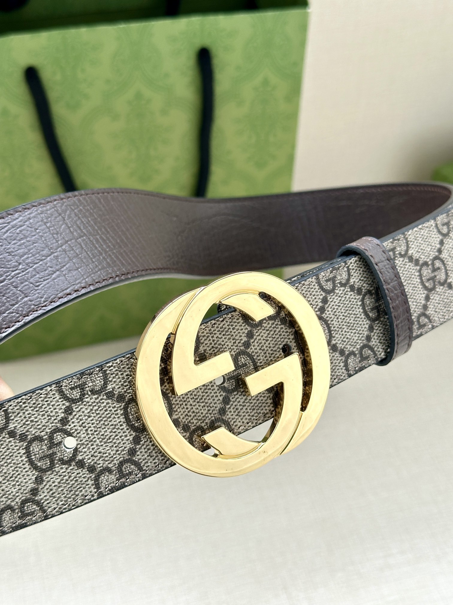 Gucci GG Marmont reversible belt featuring a beige and ebony GG Supreme canvas on one side and a polished gold-toned interlocking G buckle