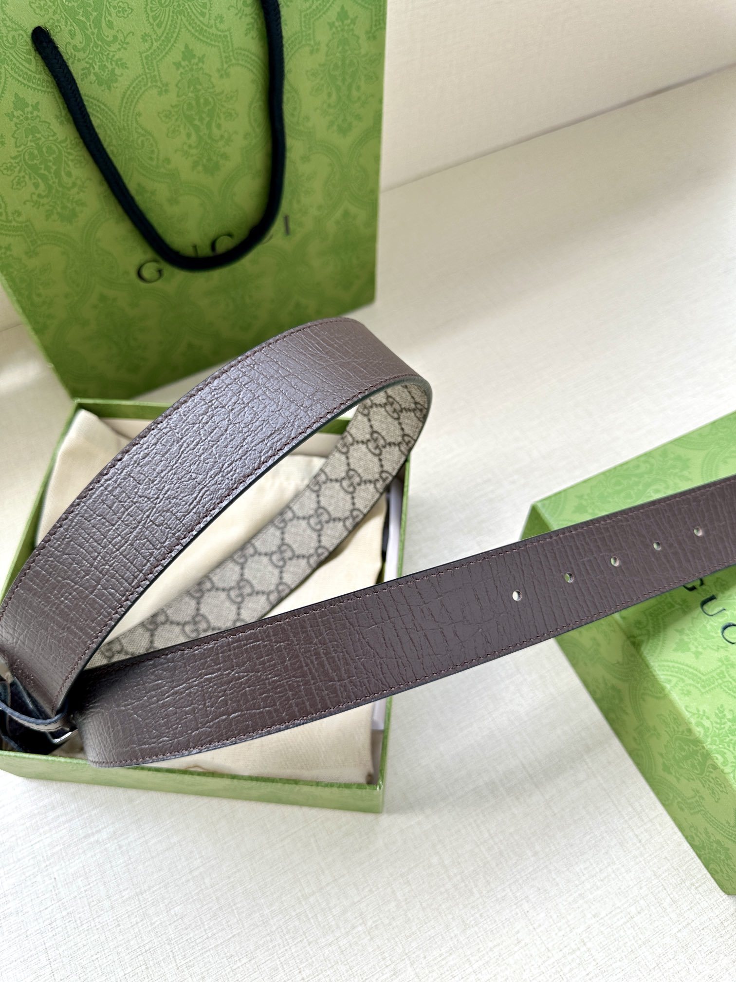 Gucci GG Marmont reversible belt featuring a beige and ebony GG Supreme canvas on one side and a polished gold-toned interlocking G buckle