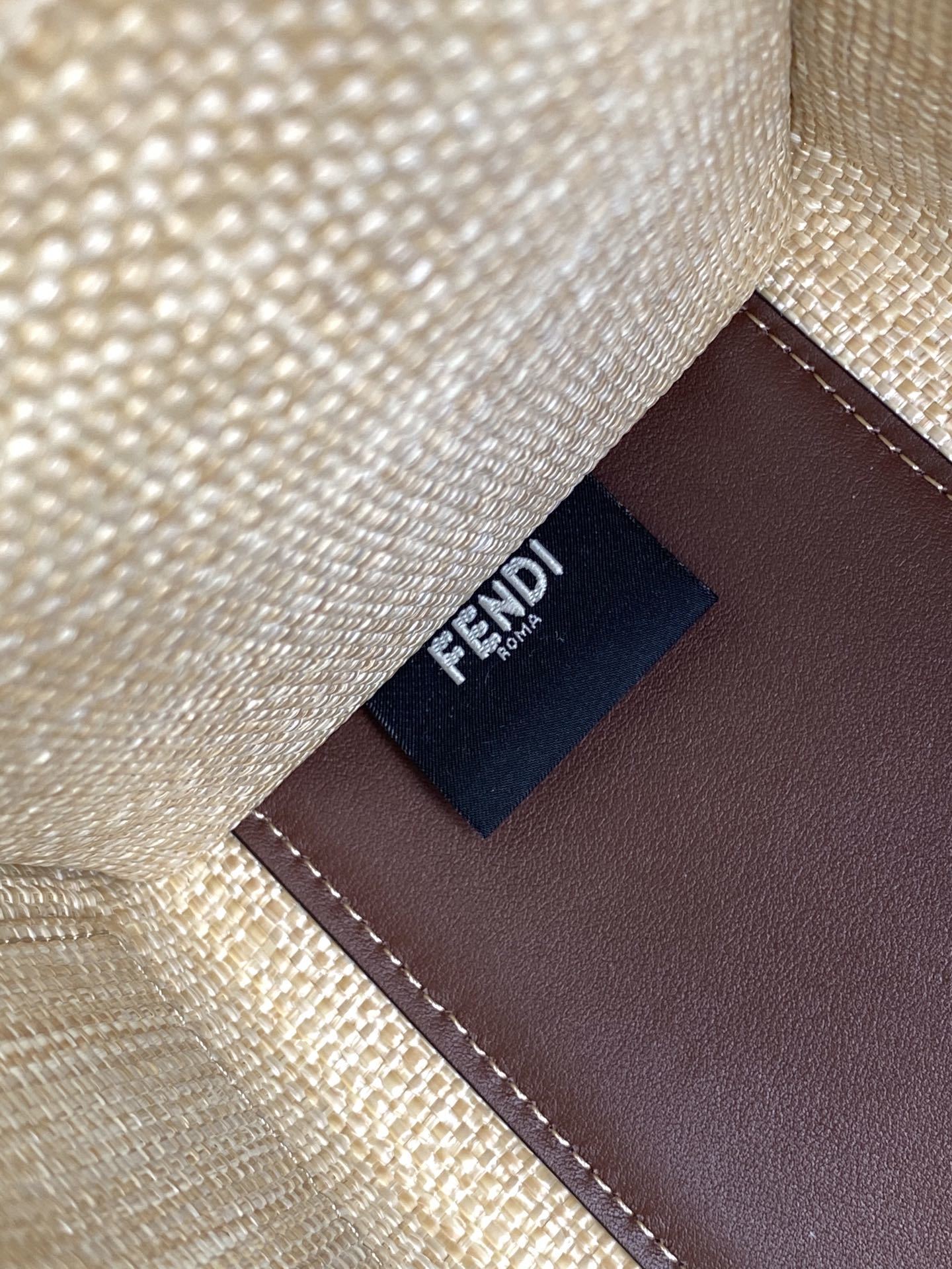Fendi Sunshine tote bag is crafted from beige natural fiber raffia with brown leather trim and prominent "Fendi Roma" lettering