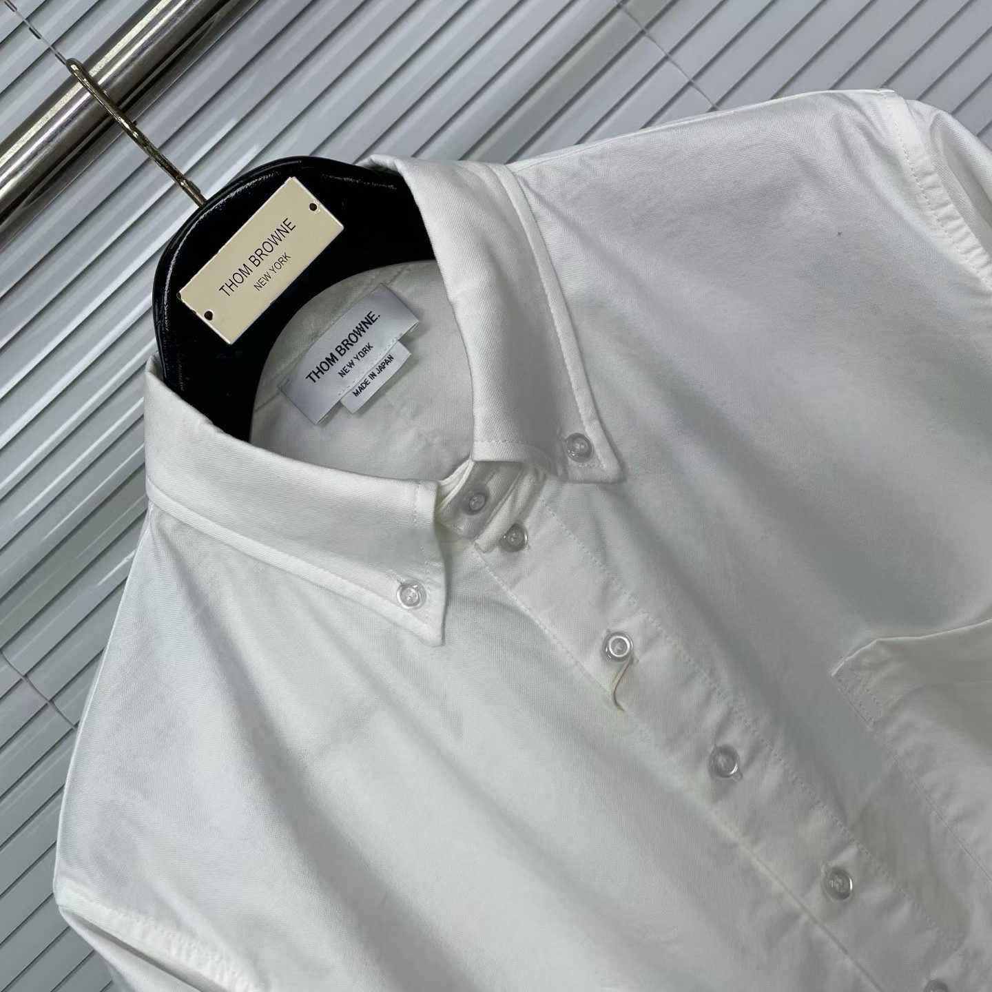Thom Browne white cotton button-down shirt featuring the signature 4-bar stripe detail on the left sleeve.