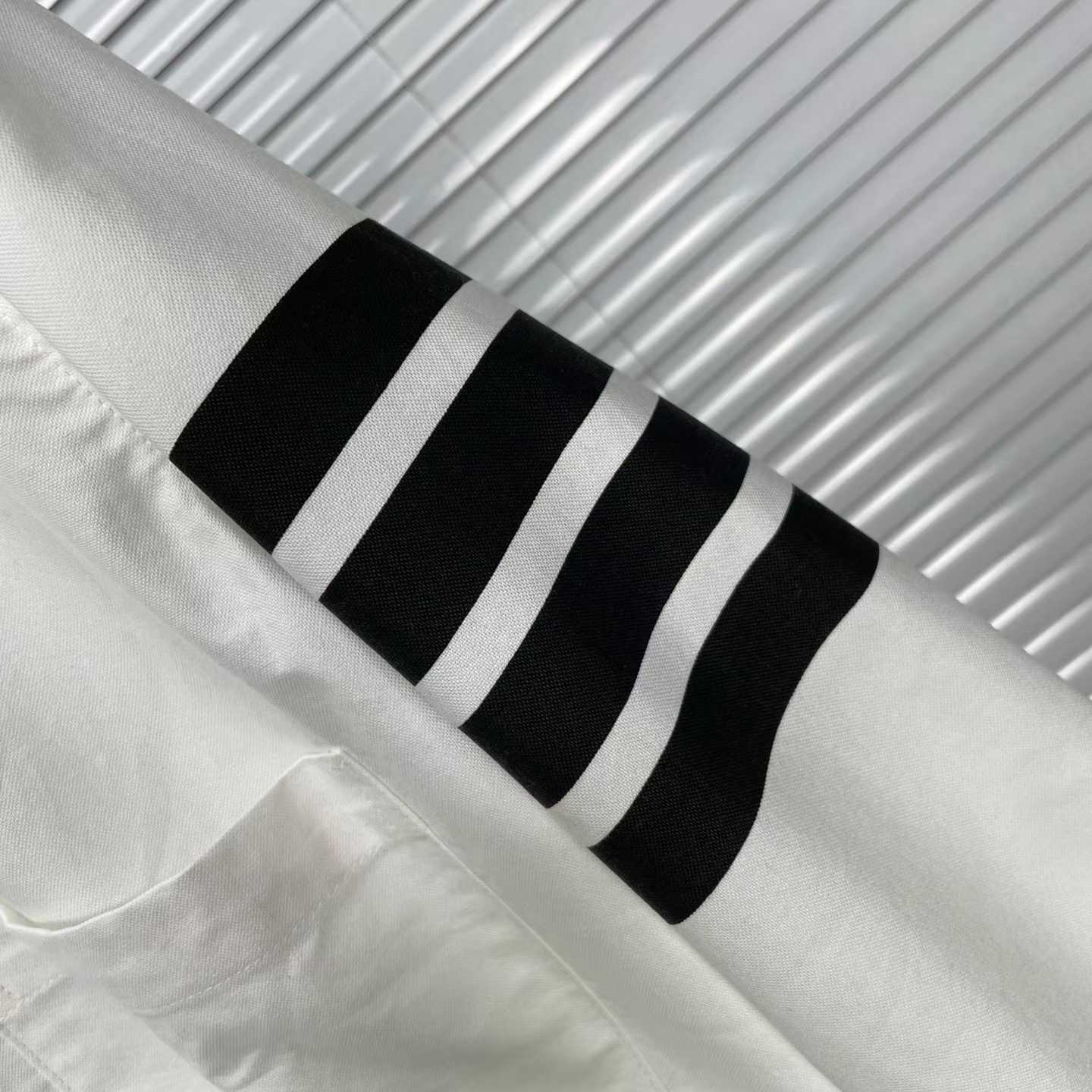 Thom Browne white cotton button-down shirt featuring the signature 4-bar stripe detail on the left sleeve.