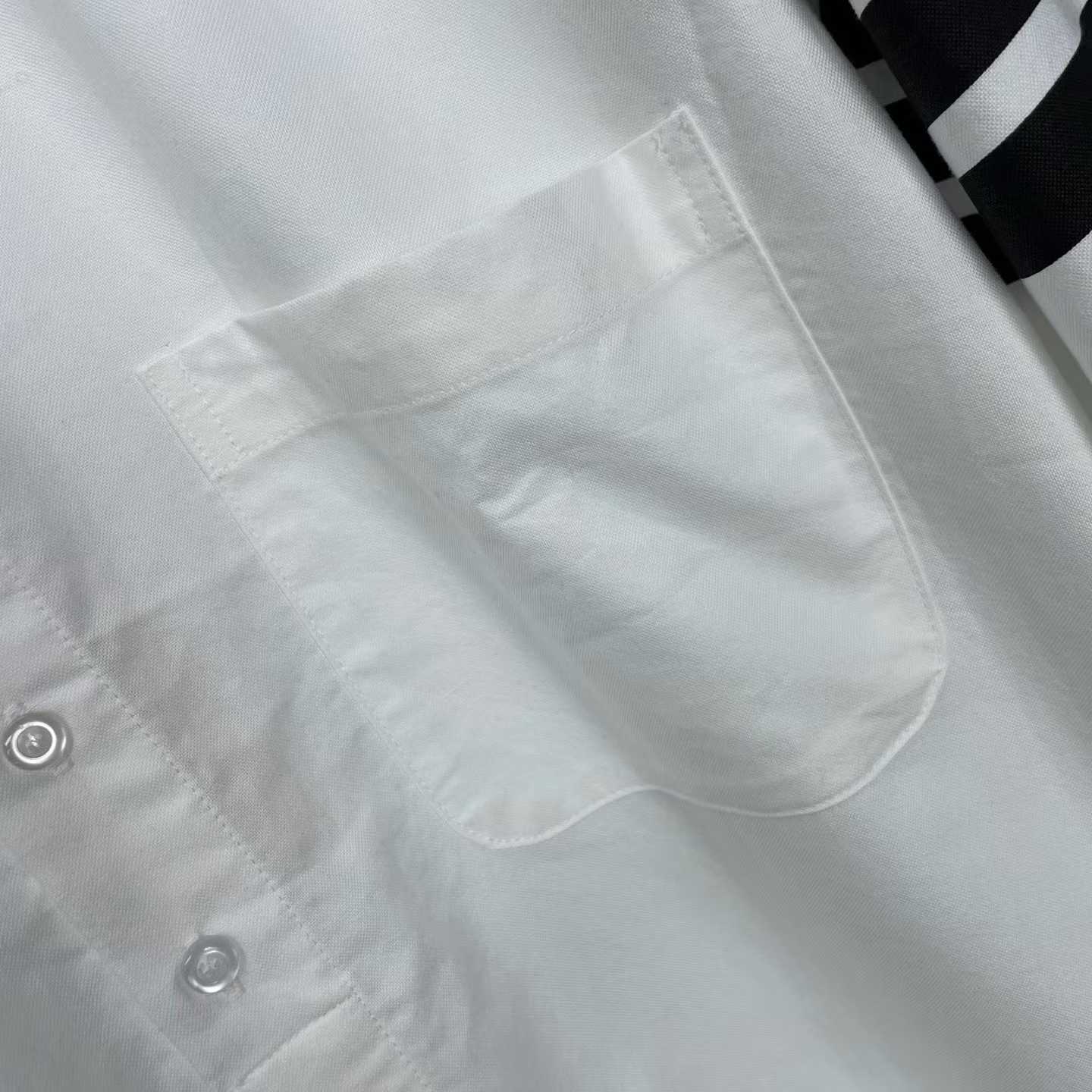 Thom Browne white cotton button-down shirt featuring the signature 4-bar stripe detail on the left sleeve.