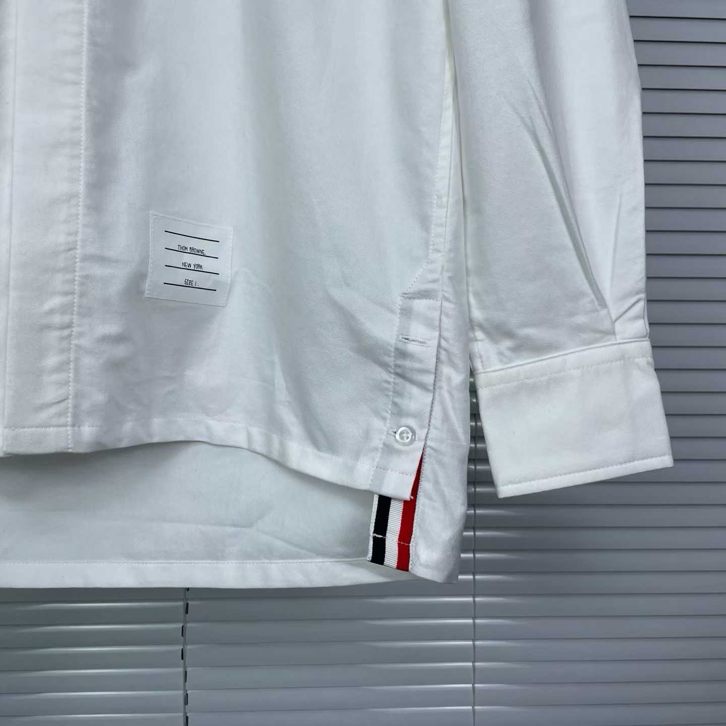 Thom Browne white cotton button-down shirt featuring the signature 4-bar stripe detail on the left sleeve.