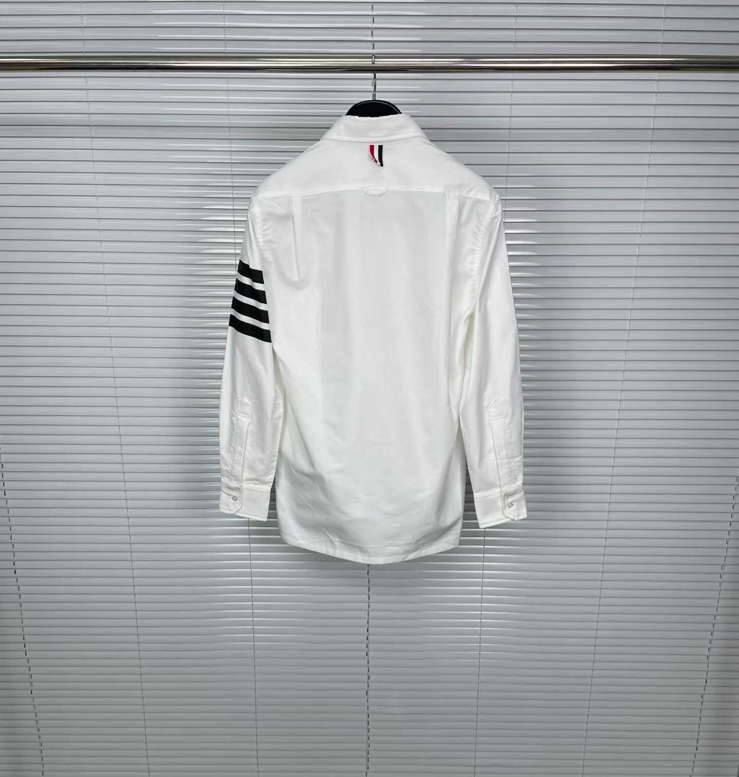 Thom Browne white cotton button-down shirt featuring the signature 4-bar stripe detail on the left sleeve.