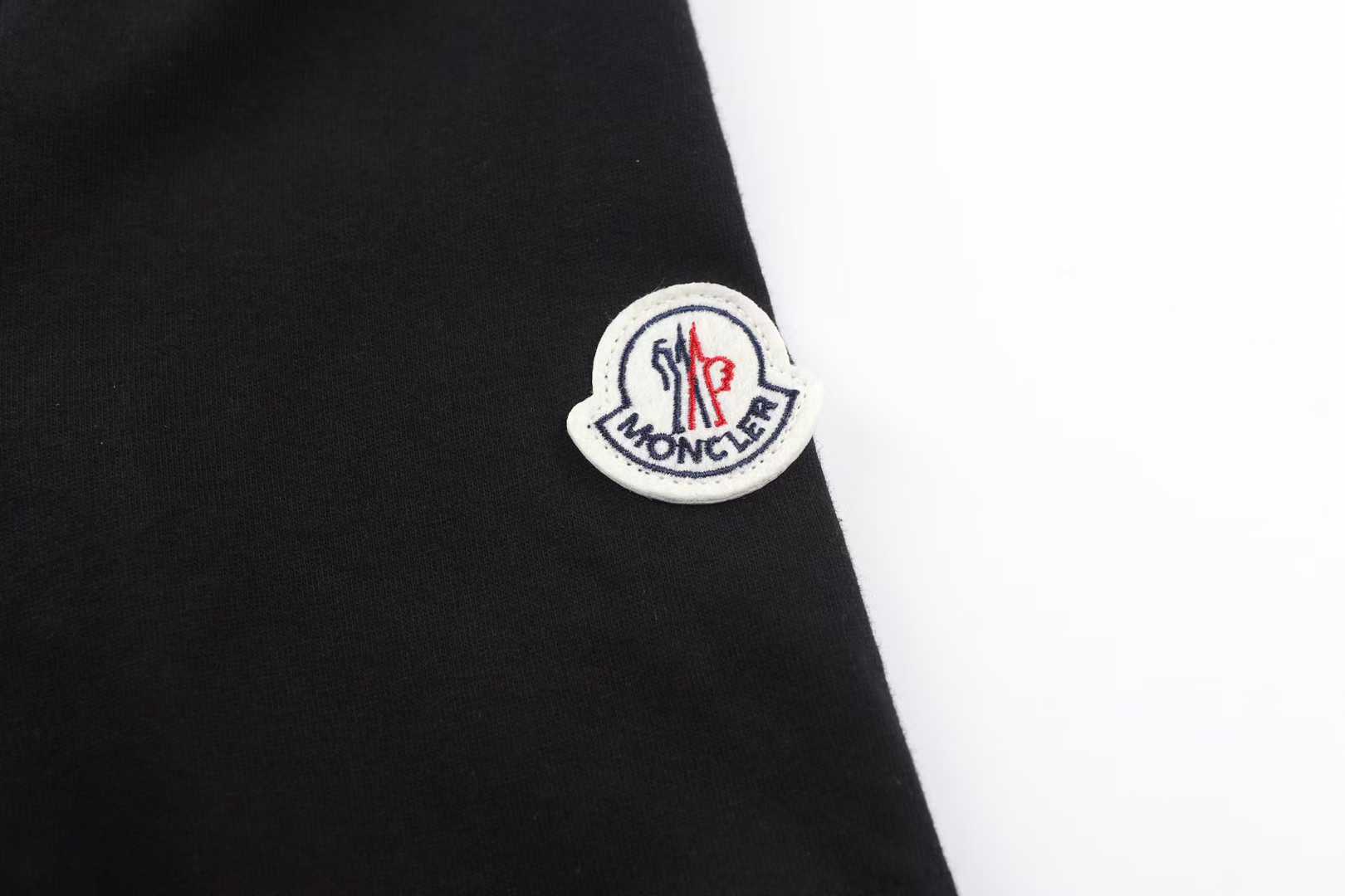 Moncler Striped-Trim Detail-Appliqué T-Shirt is a luxury cotton jersey crewneck featuring a distinctive mascotte logo patch on the chest and striped detailing on the neckline